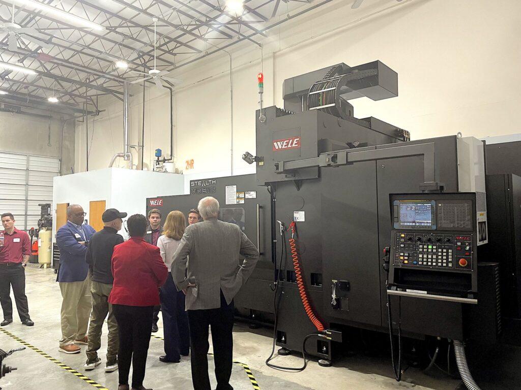 A group of people standing around an industrial machine.